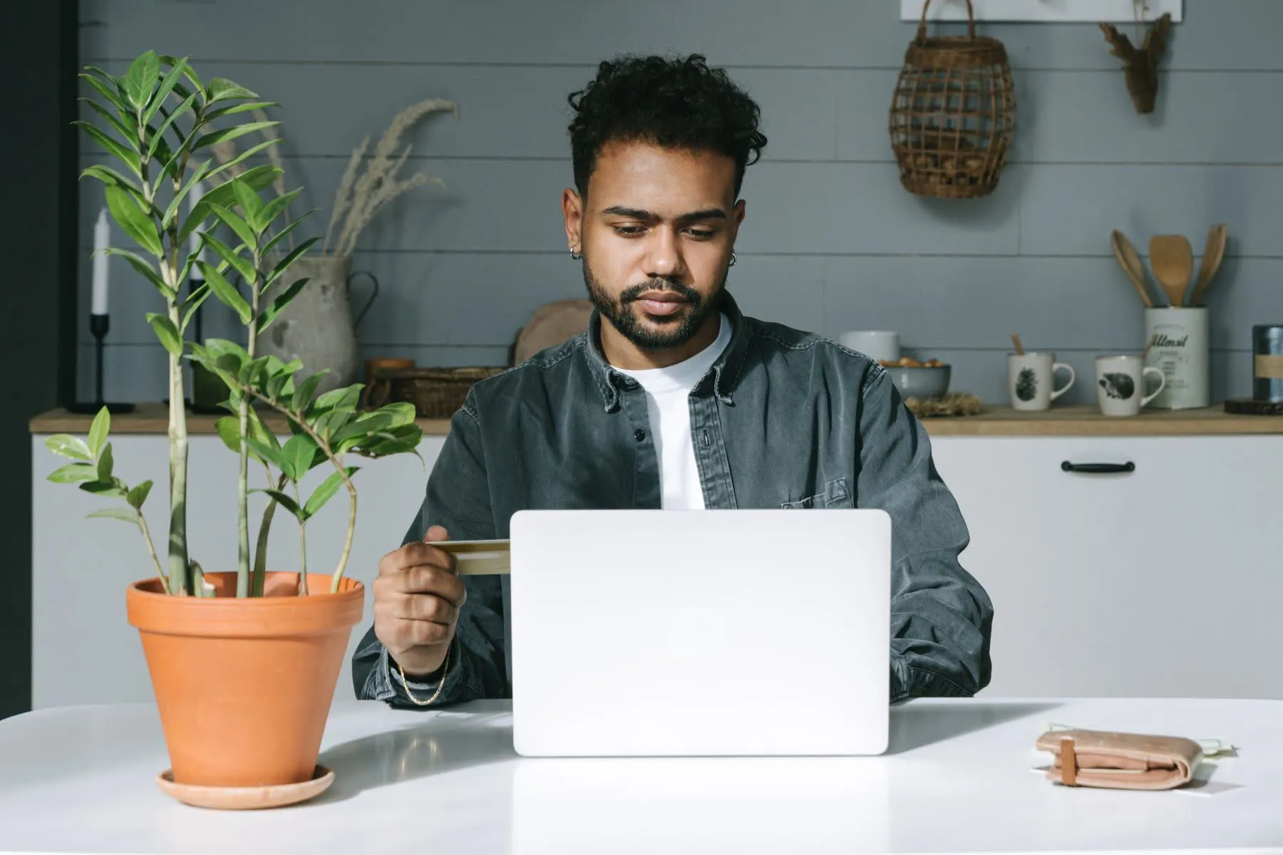 Pessoa se cadastrando no laptop, com o cartão em mãos, em casa.